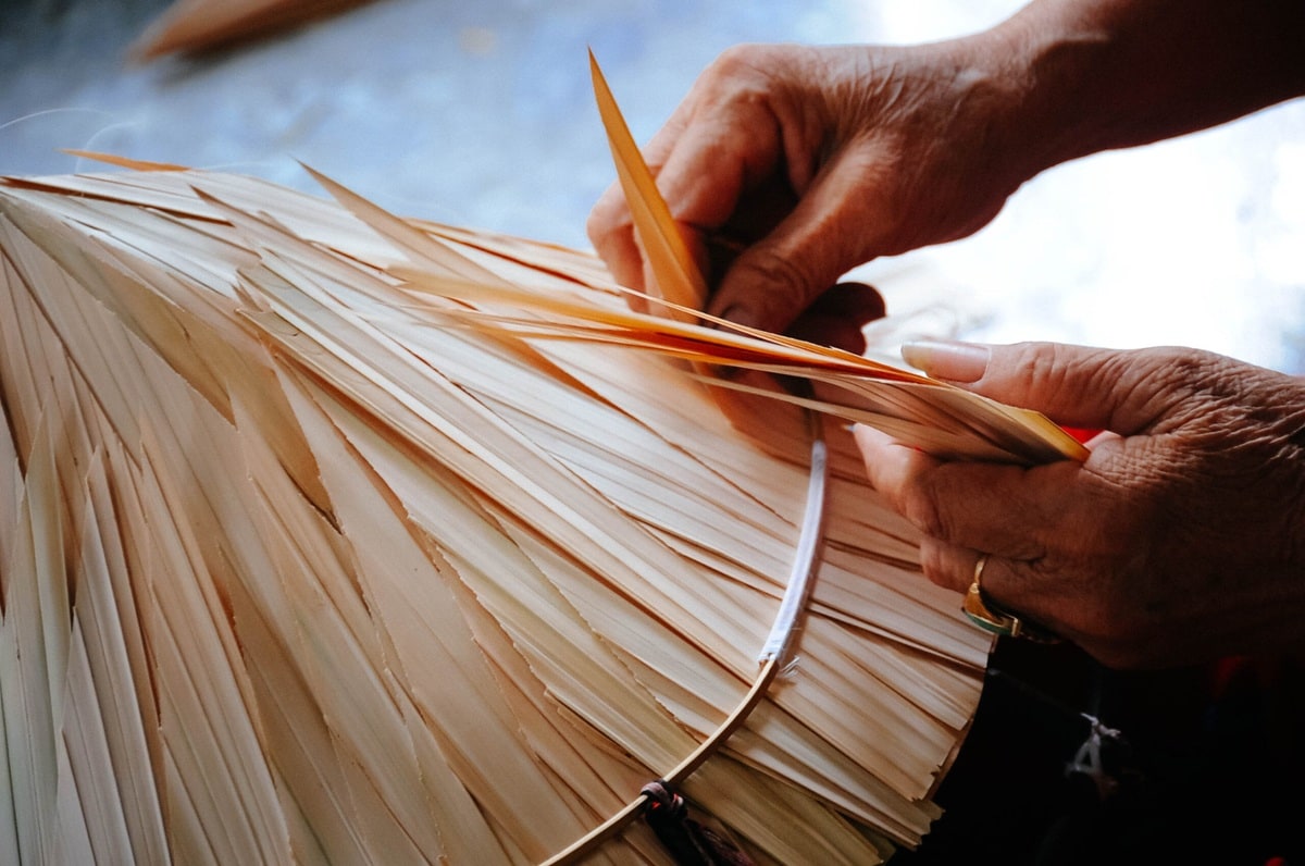 Each layer of leaf is stacked on top of the other and tightly secured with nylon thread onto a conical bamboo frame 